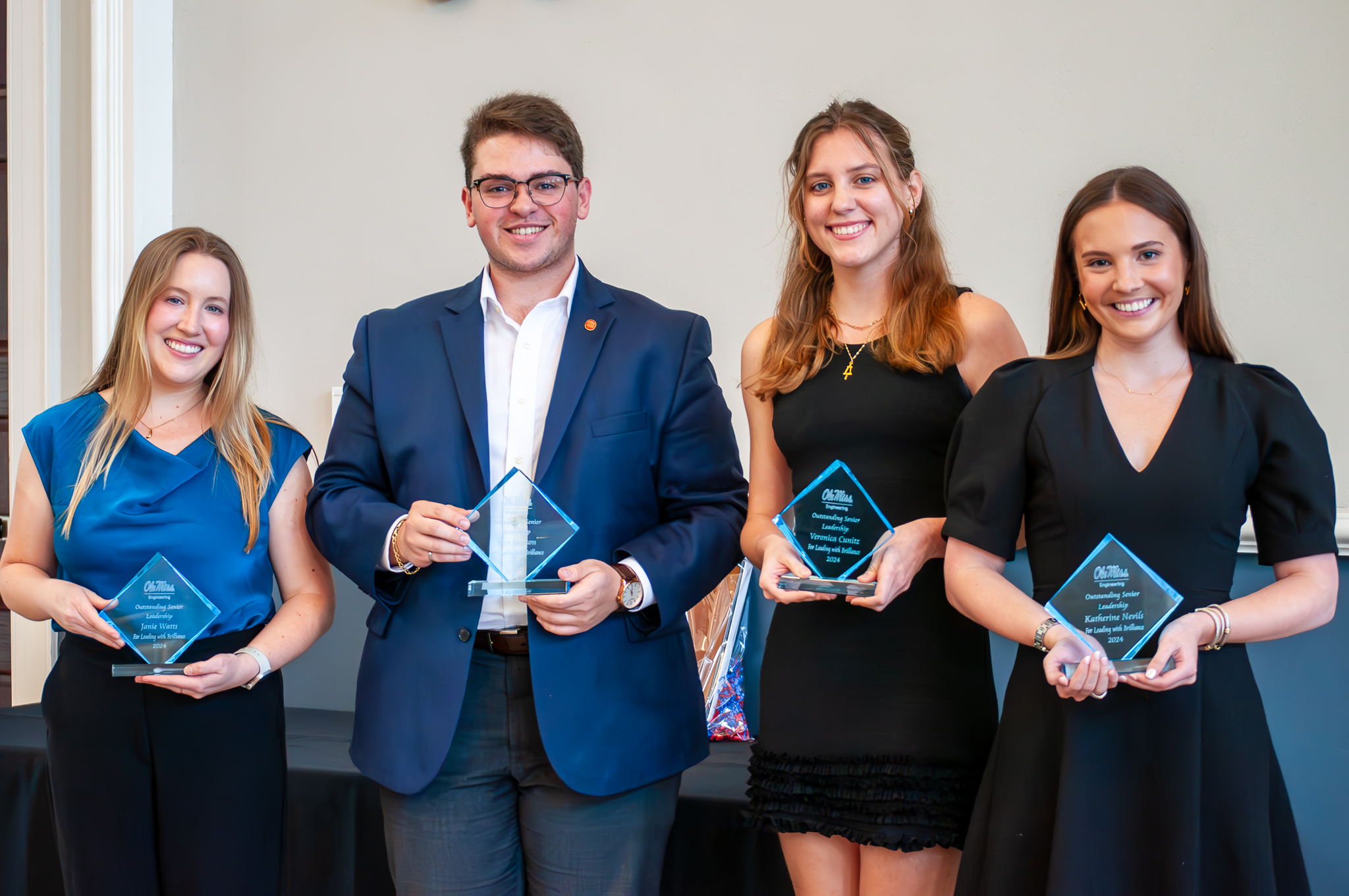 Four students smiling and holding awards.