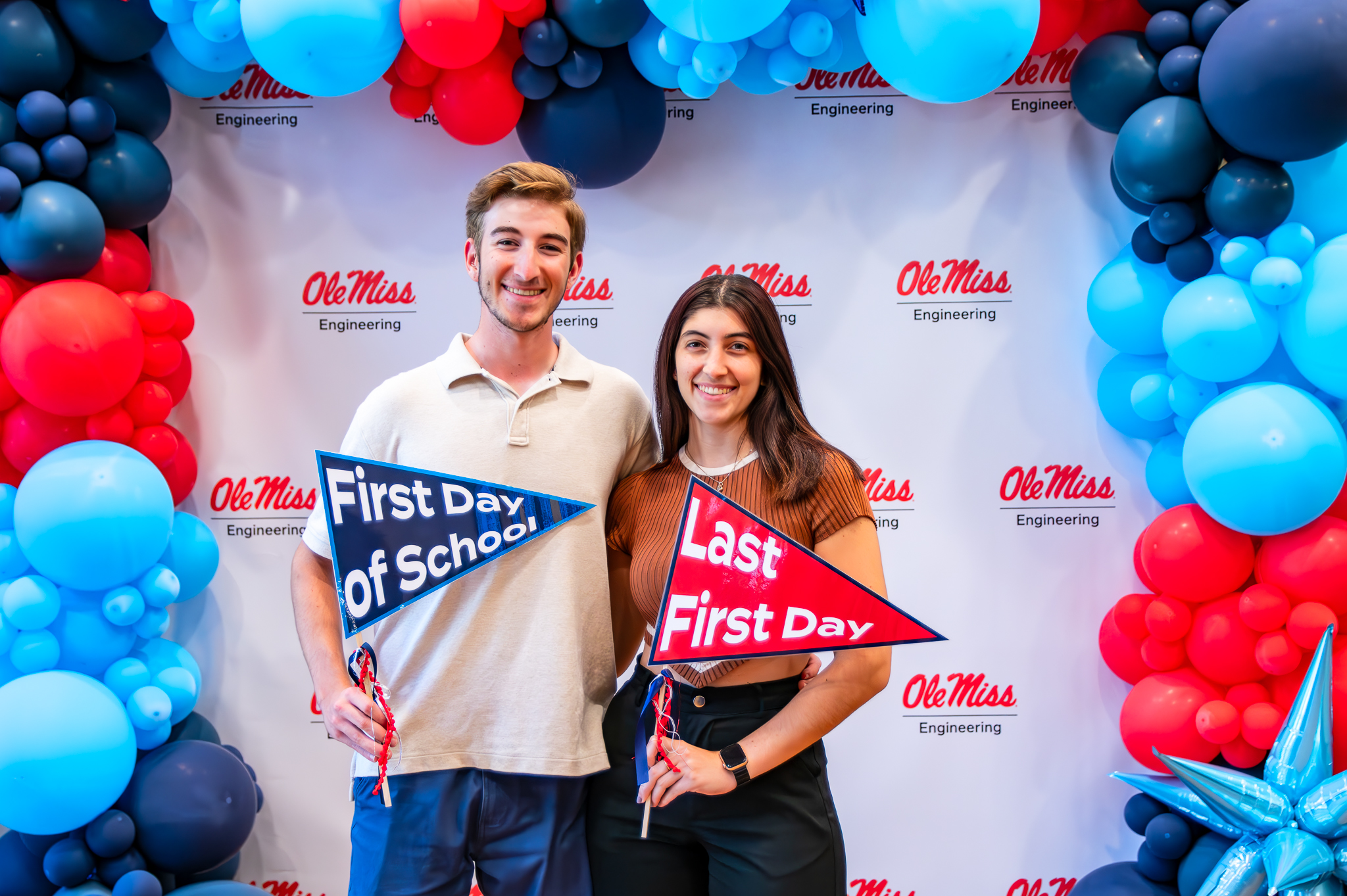 Students posing for a photo holding flags that say first day of school and last first day