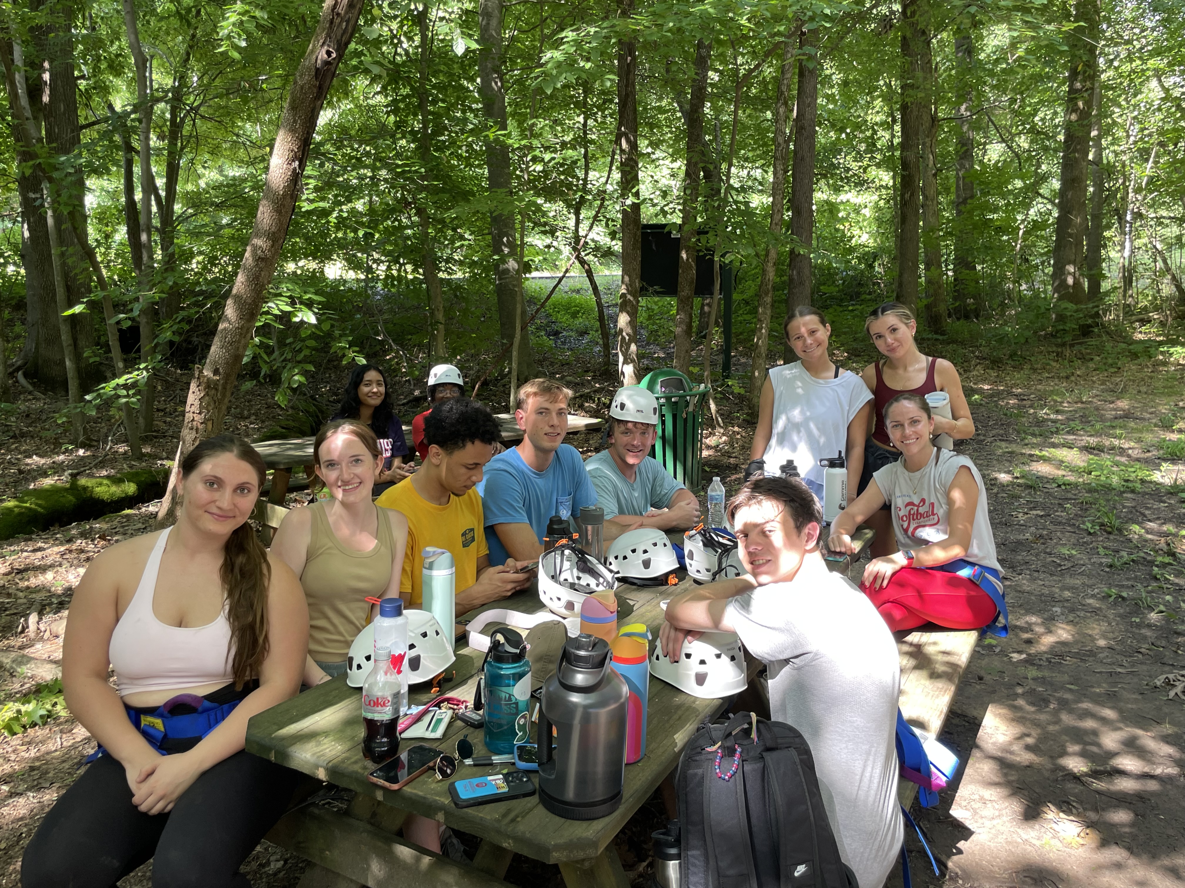 2025 REU students sit outdoors taking a break from a ropes course