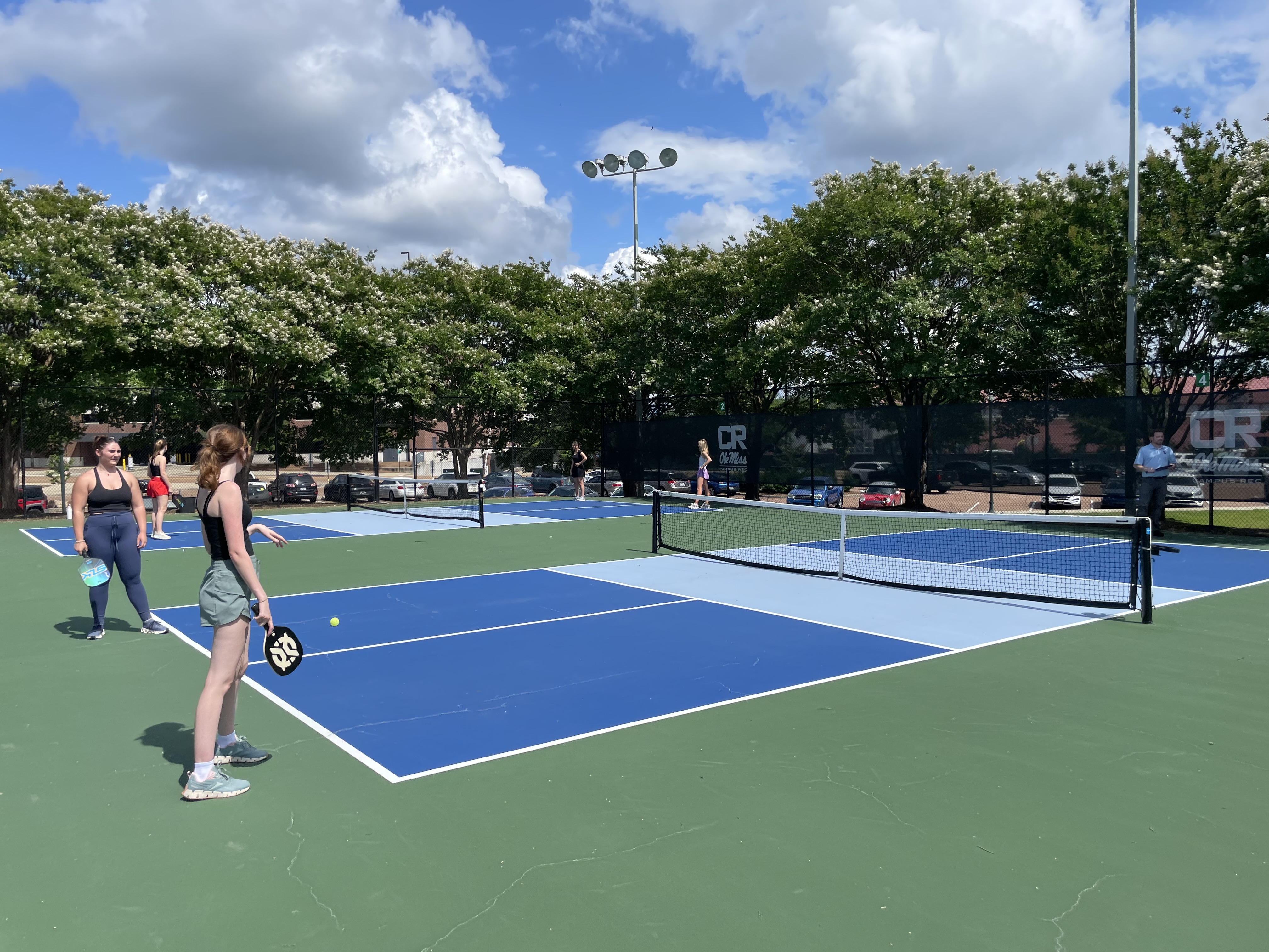 Two students holding rackets on a pickleball court