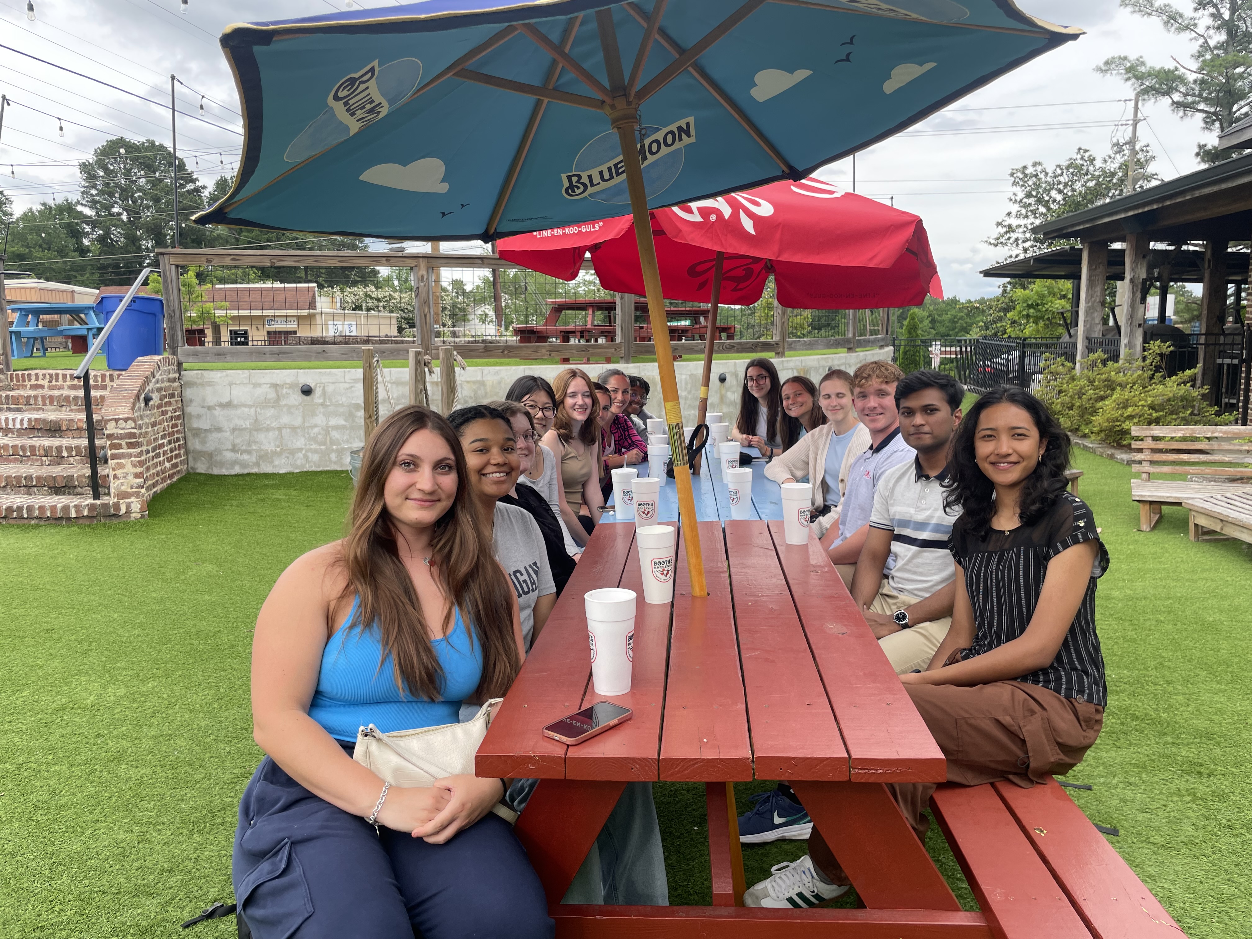 2025 REU students sit at a picnic table at an outdoor restaurant