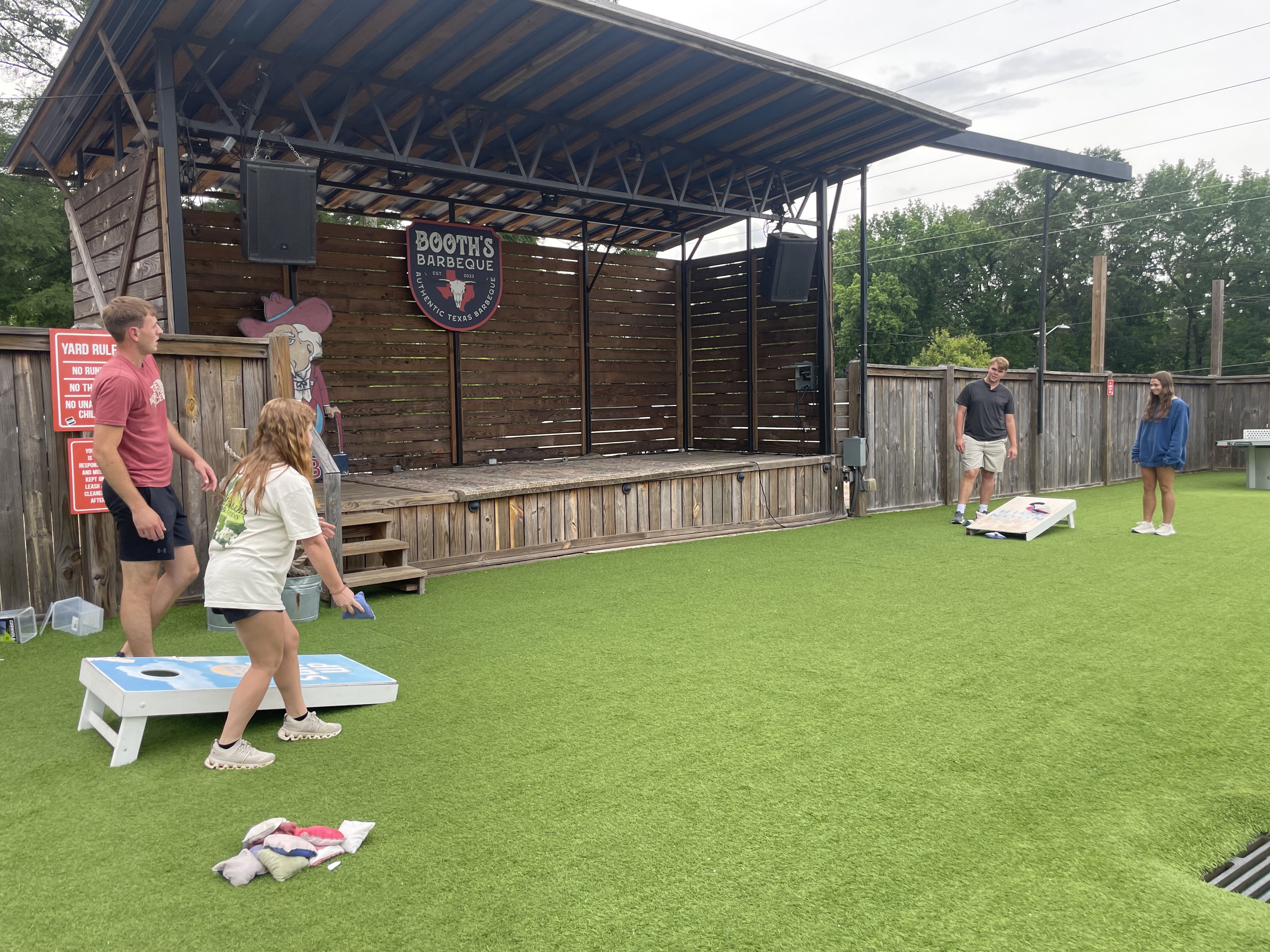Four REU 2025 students play cornhole outdoors