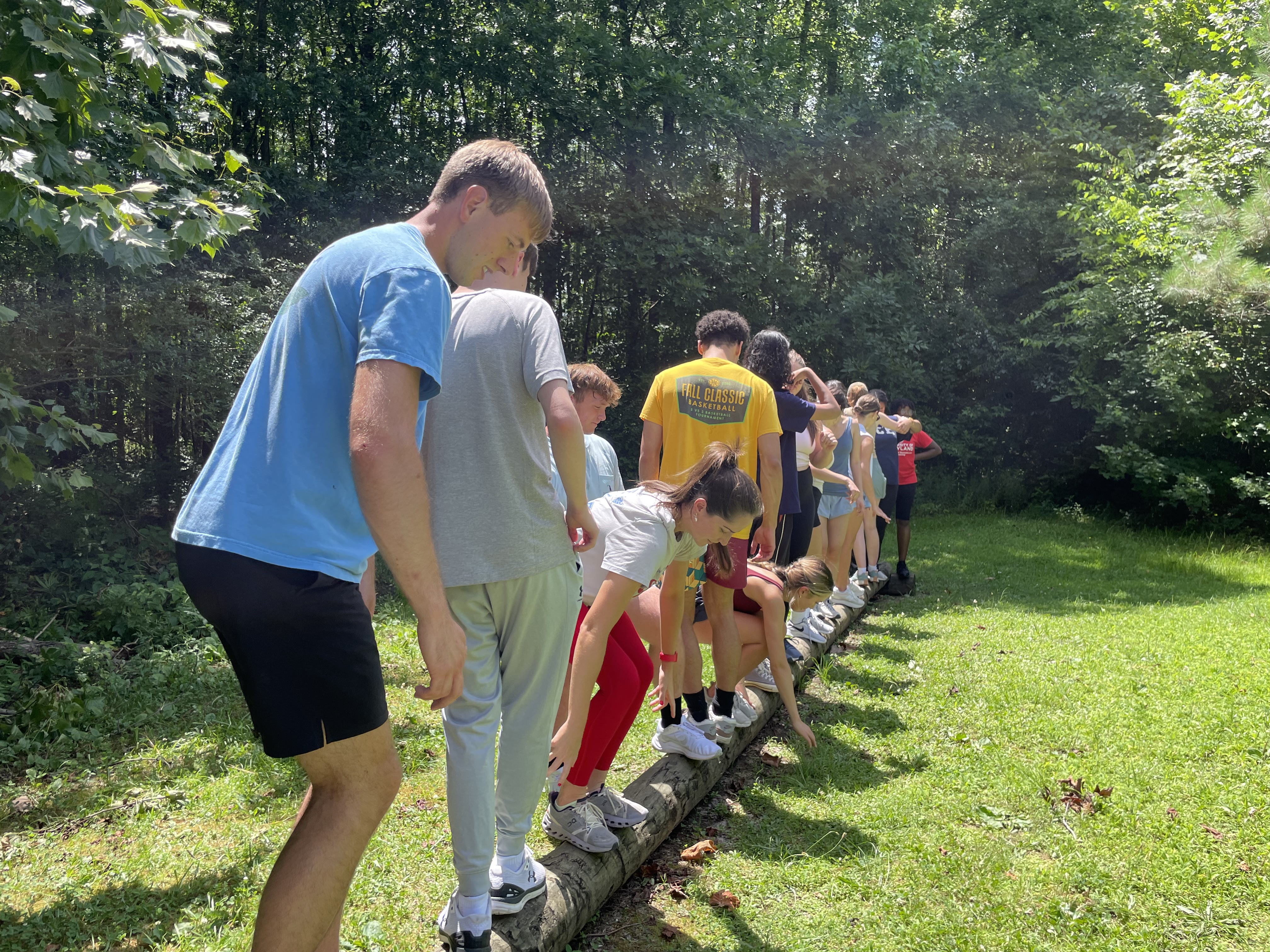 A group of students balance together on a log