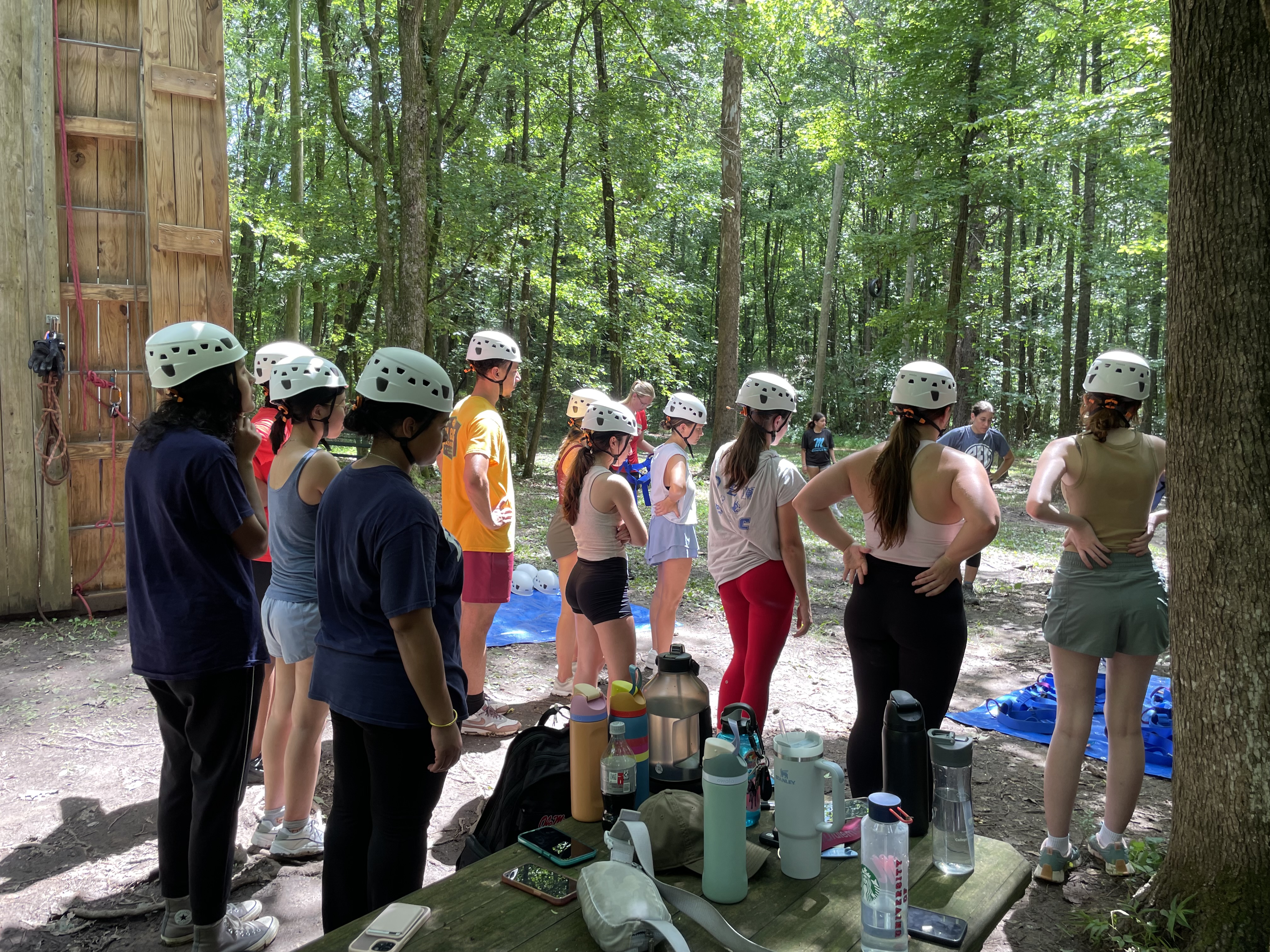 A group of students in helmets and harnesses stand in a semi-circle